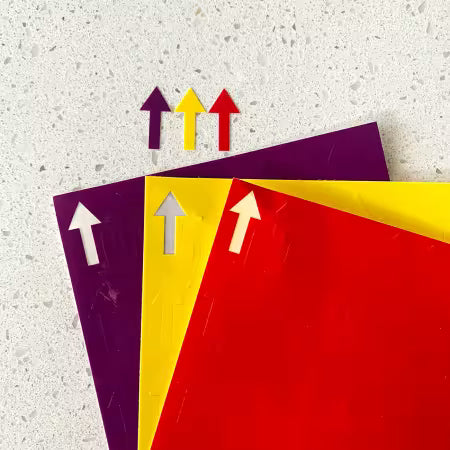 Three colorful paper sheets with arrow cutouts on a textured surface