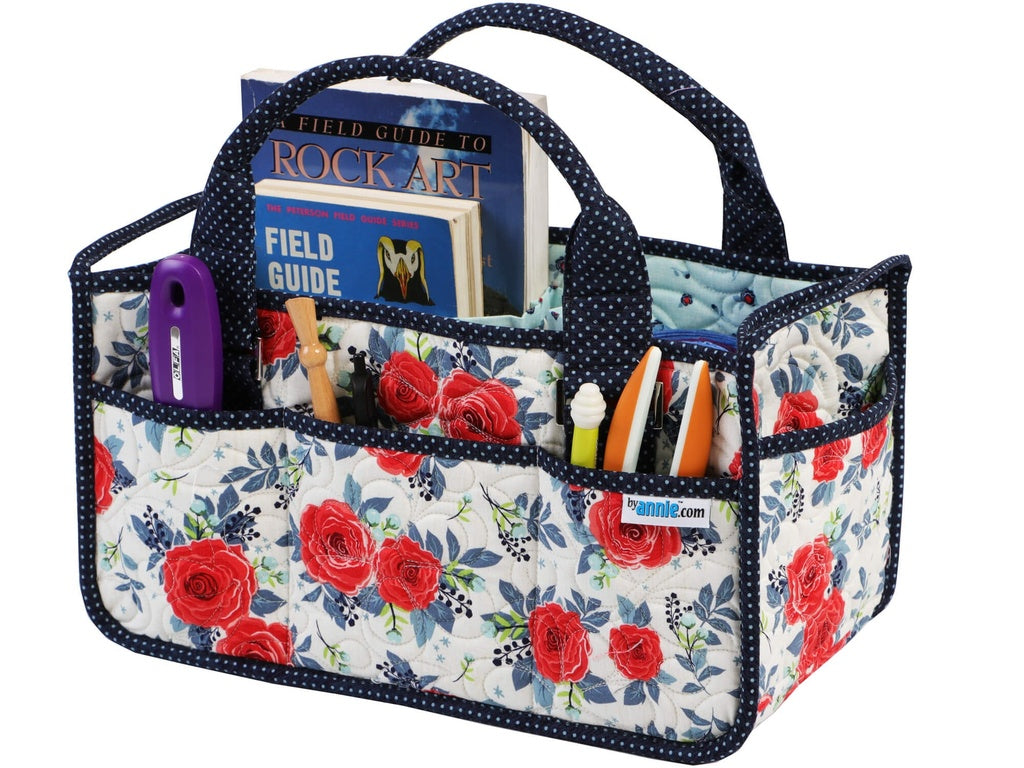 Floral-patterned tote bag with books and stationery items on a white background