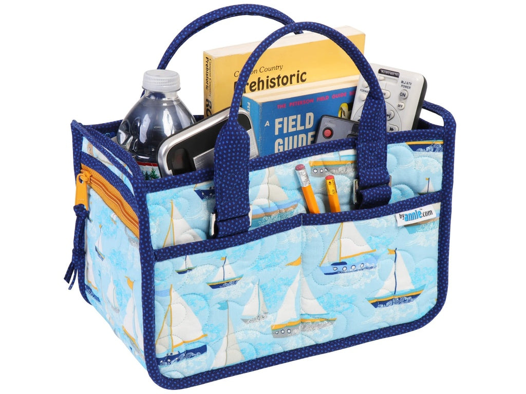 Multifunctional bag with sailboat design filled with items on a white background