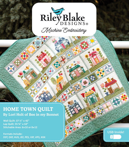 Embroidery design book for 'Home Town Quilt' by Riley Blake Designs with a quilt displayed on a stand.