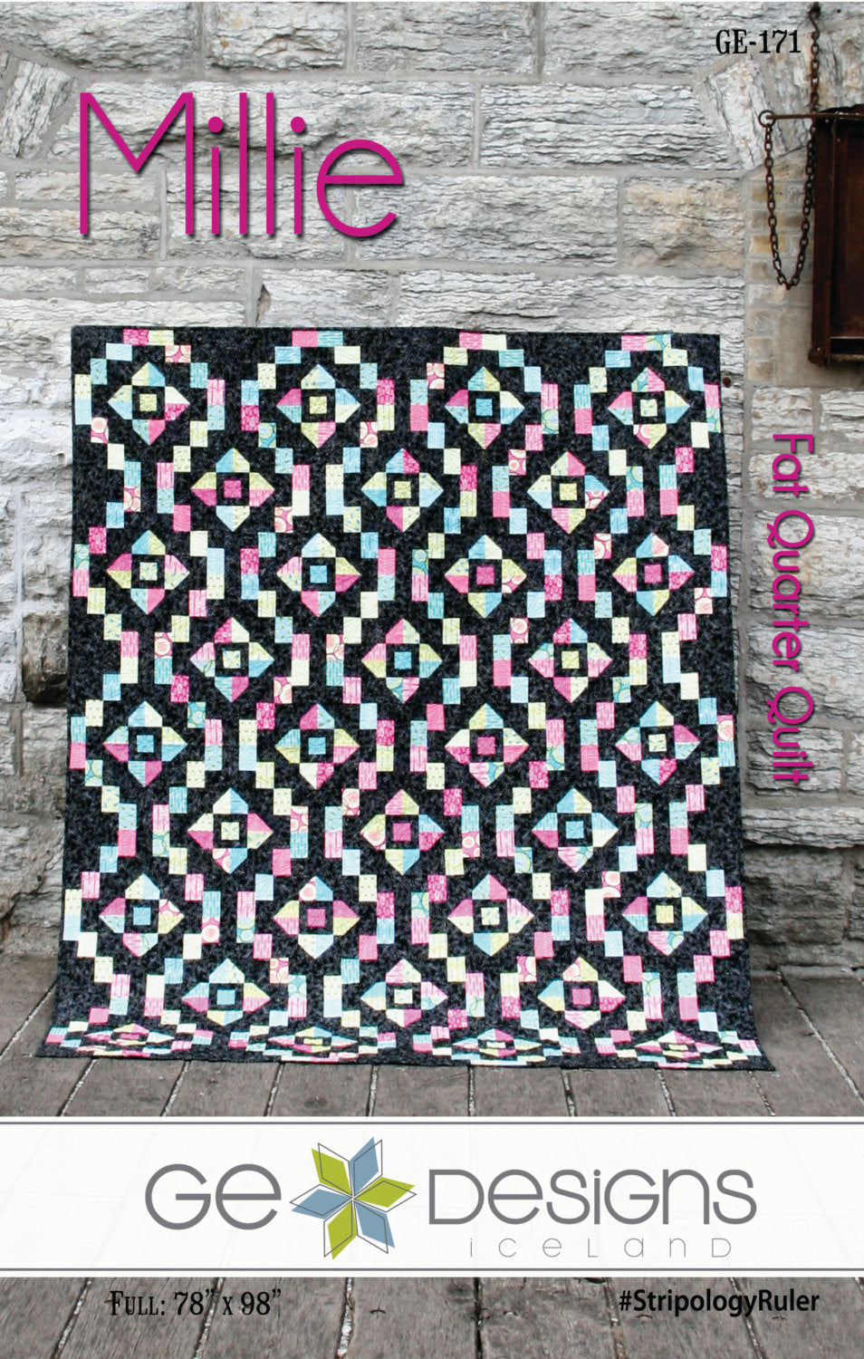 Quilt with geometric pattern on a wooden floor, featuring the brand 'GE Designs'.