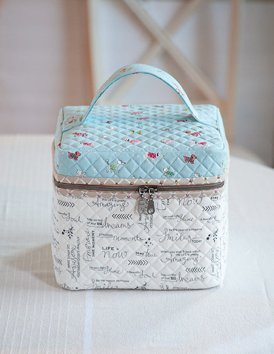 Quilted fabric bag with light blue top and patterned bottom on a white surface.