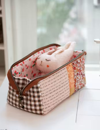 Fabric pouch with checkered pattern and text, containing a plush toy, on a light surface.