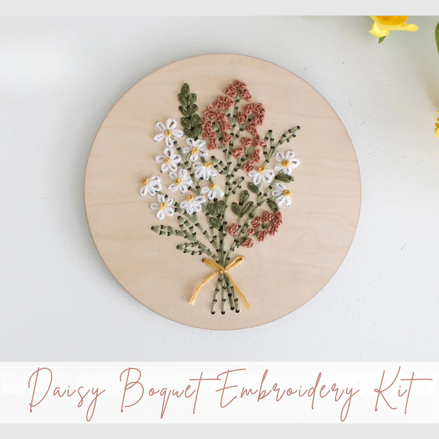 Embroidery hoop with a daisy bouquet design on a white background