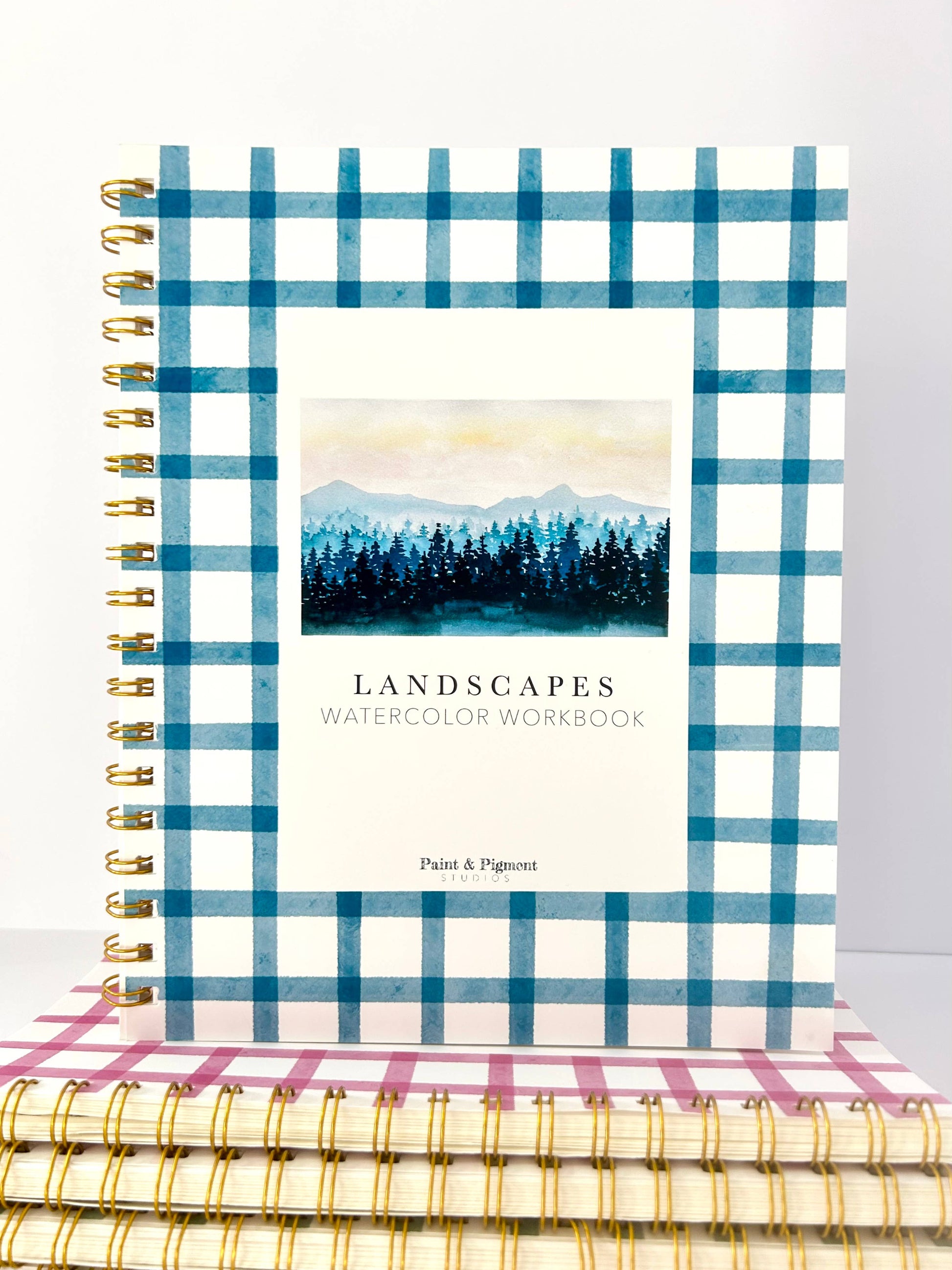 Notebook with blue plaid cover and watercolor landscape design on a white background