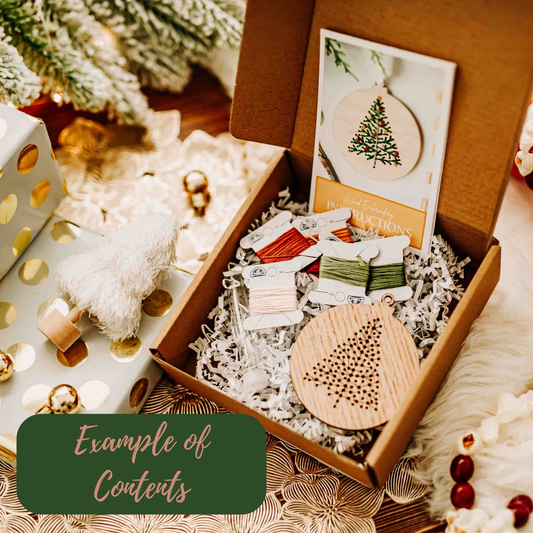 Wooden ornament kit with instructions and materials in a box, surrounded by Christmas decorations.